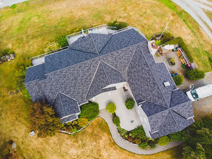 Overhead view of a large multi-gable home with new composite shingle roofing